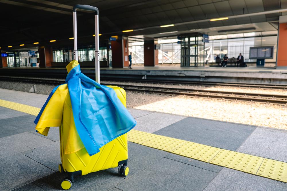 Yellow valise with ukrainian flag at train station
