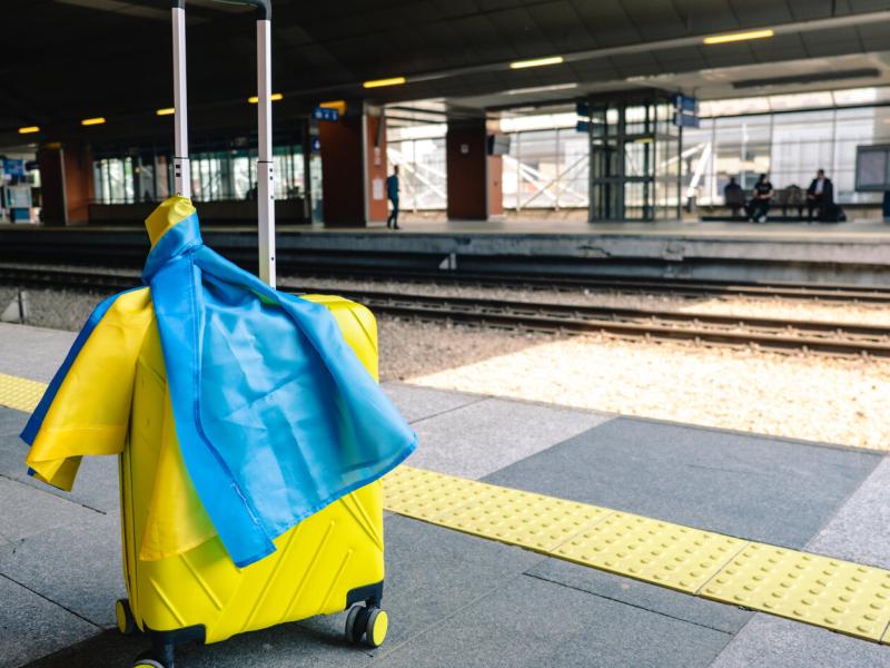 Yellow valise with ukrainian flag at train station