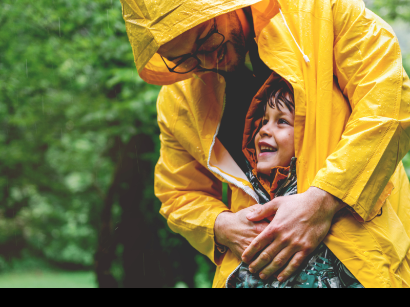 man protecting child from getting wet