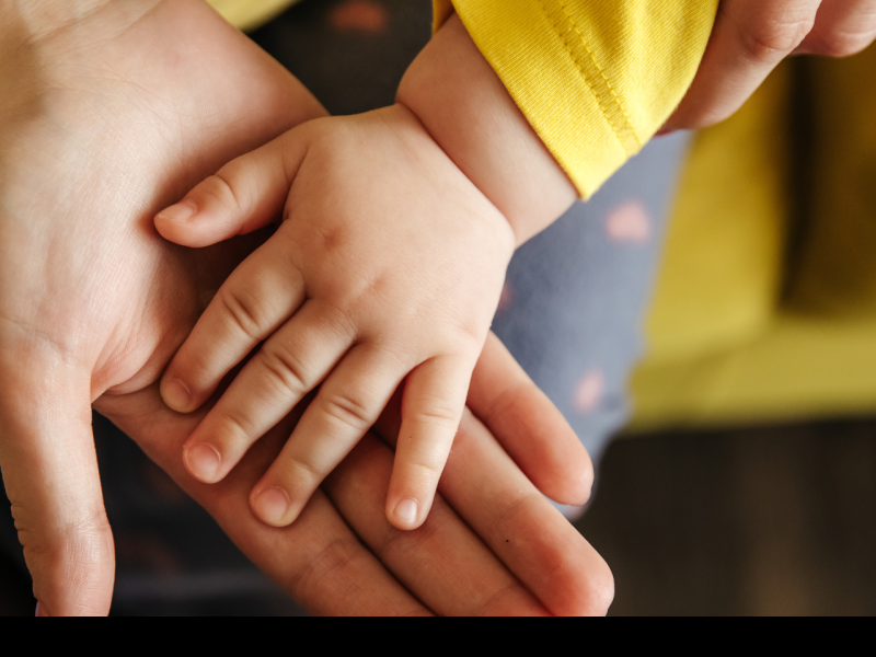 older and younger person holding hands